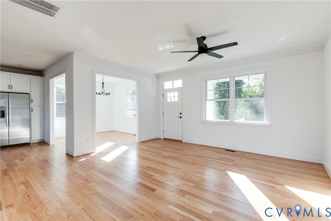 637 Ellens Haven Alley, Highland Grove, Richmond, VA 23222 Open interior featuring wood-finish flooring, white cabinetry, a multi-pane door with transom, large windows, and a matte black ceiling fan