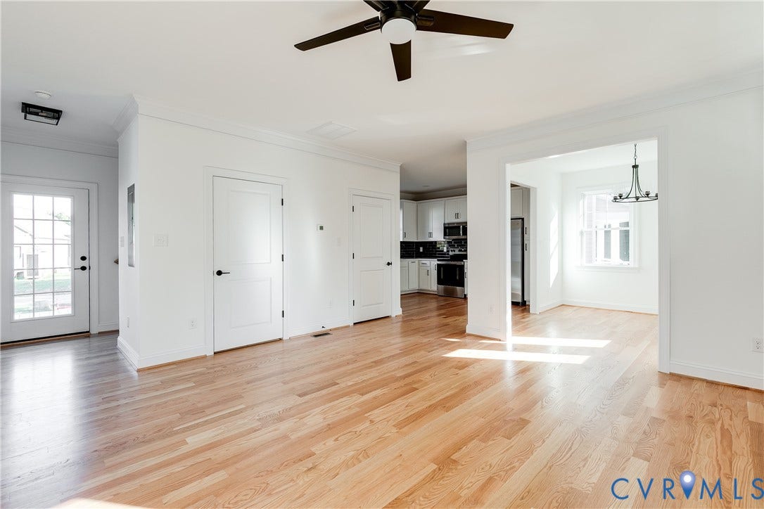 637 Ellens Haven Alley, Highland Grove, Richmond, VA 23222 Open interior space featuring light wood-finish flooring, white paneled doors, a ceiling fan with integrated lighting, and a multi-pane glass entry door