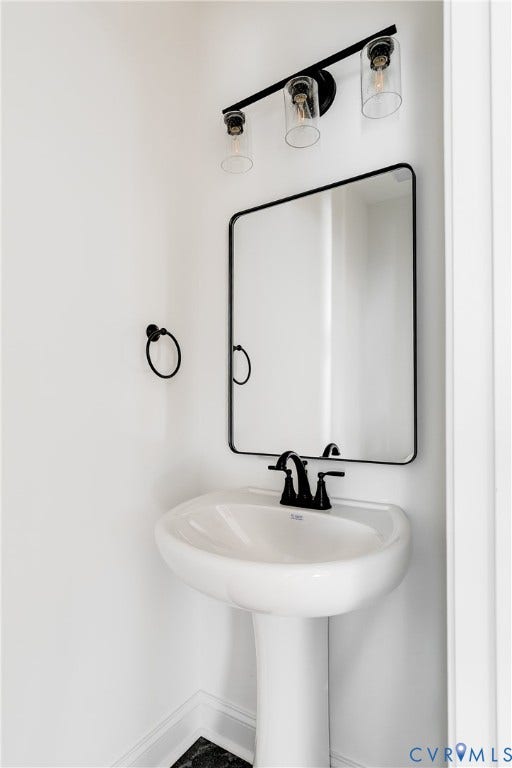 637 Ellens Haven Alley, Highland Grove, Richmond, VA 23222 White porcelain pedestal sink with a matte black widespread faucet, rectangular mirror with a matte black frame, and a three-light vanity fixture featuring clear glass cylindrical shades