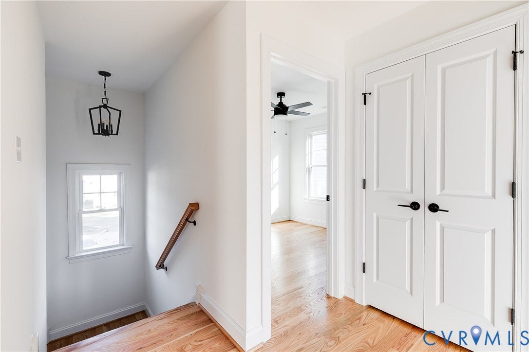 637 Ellens Haven Alley, Highland Grove, Richmond, VA 23222 Wood-finish flooring, white paneled double doors with matte black hardware, wooden handrail, and geometric metal pendant lighting