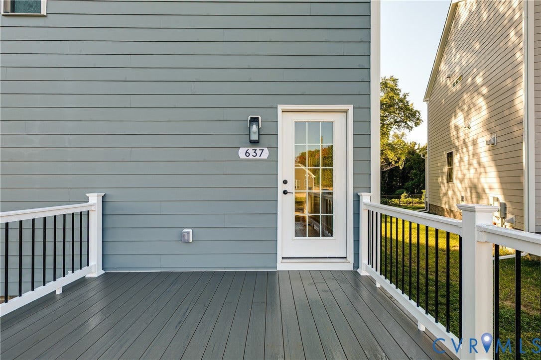 637 Ellens Haven Alley, Highland Grove, Richmond, VA 23222 Composite deck featuring white railings with vertical black balusters, lap siding exterior, and a multi-pane glass entry door with a wall-mounted light fixture