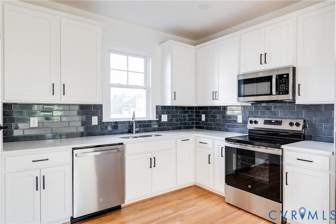 637 Ellens Haven Alley, Highland Grove, Richmond, VA 23222 Kitchen featuring white shaker-style cabinetry, dark subway tile backsplash, solid-surface countertops, stainless steel appliances, and wood-finish flooring