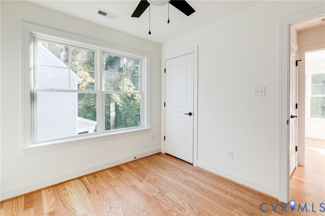 637 Ellens Haven Alley, Highland Grove, Richmond, VA 23222 Wood-finish flooring, multi-pane window with grid detailing, matte black door hardware, and a ceiling fan