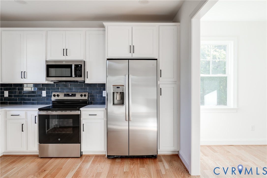 637 Ellens Haven Alley, Highland Grove, Richmond, VA 23222 Kitchen featuring white cabinetry with matte black hardware, stainless steel appliances, dark subway tile backsplash, and wood-finish flooring
