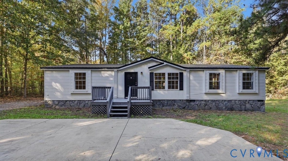75 Claybank Road, Cumberland, VA 23040 Light-colored siding exterior featuring a stone-veneer foundation, black window shutters, a front porch with railing, and an expansive concrete parking pad