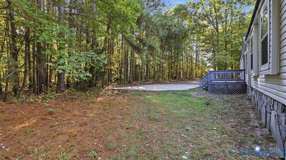 75 Claybank Road, Cumberland, VA 23040 Rear exterior featuring horizontal siding, stone veneer foundation, concrete patio, and wooden deck with lattice skirting