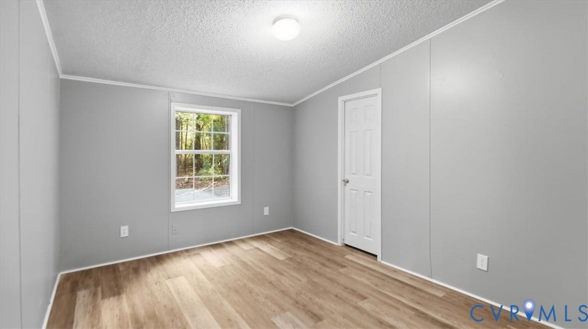 75 Claybank Road, Cumberland, VA 23040 Neutral-toned wall panels, wood-finish flooring, single-hung window with muntins, and a flush-mount ceiling light fixture