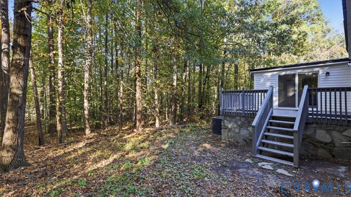 75 Claybank Road, Cumberland, VA 23040 Rear exterior featuring a raised wooden deck with balustrades, stone foundation detailing, and sliding glass entry