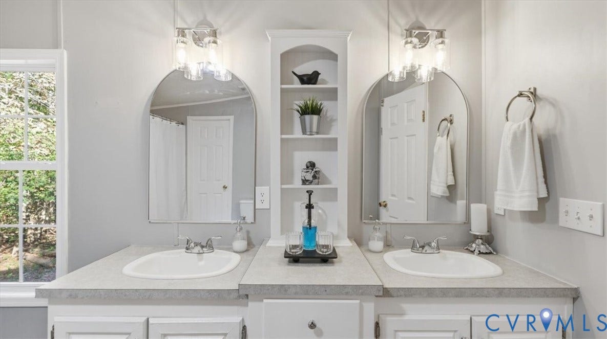 75 Claybank Road, Cumberland, VA 23040 Double vanity featuring dual arched mirrors, integrated shelving, white cabinetry, and brushed nickel fixtures