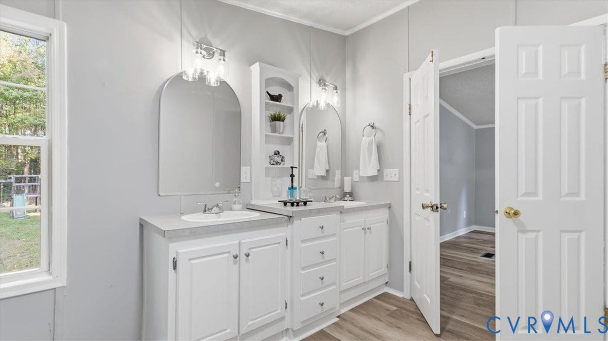 75 Claybank Road, Cumberland, VA 23040 Dual-sink vanity with light-tone countertops, arched vanity mirrors, integrated shelving, and contemporary wall-mounted lighting fixtures