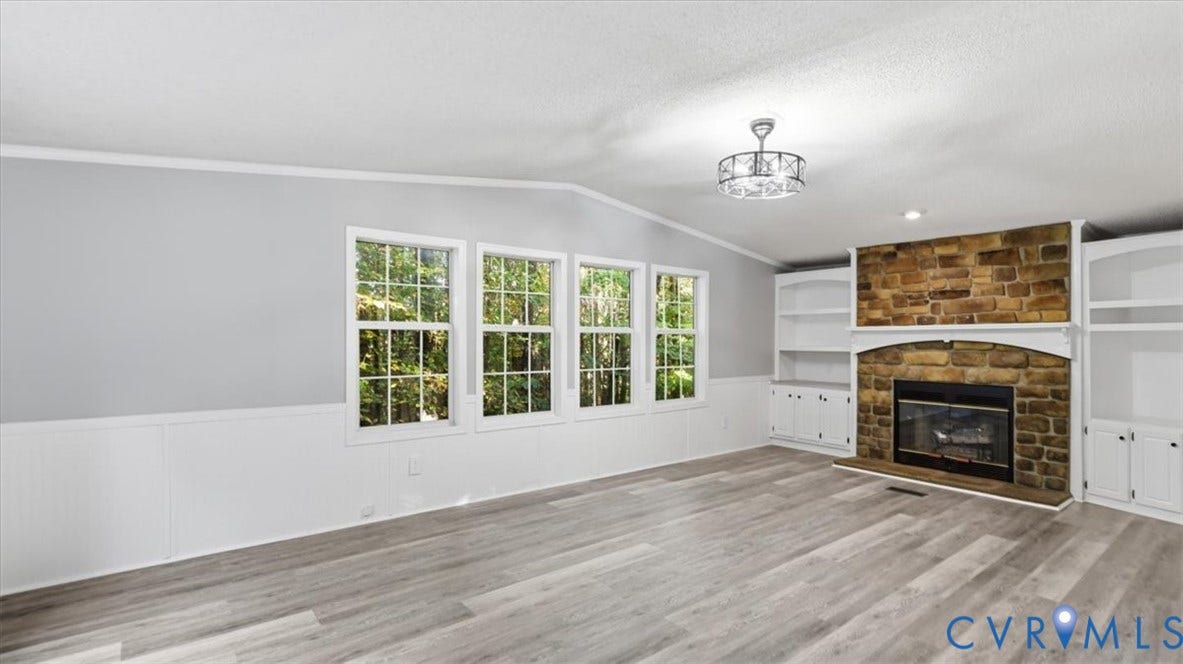 75 Claybank Road, Cumberland, VA 23040 Living area featuring stone-clad fireplace, wood-finish flooring, built-in shelving, white wainscoting, and multi-pane windows