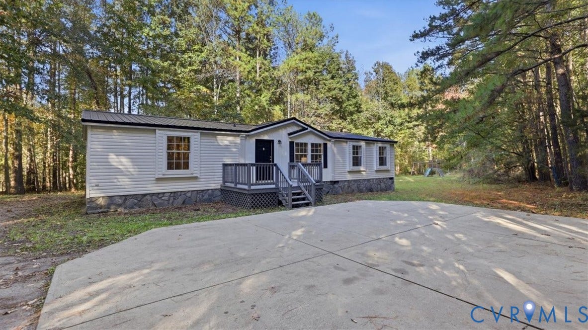 75 Claybank Road, Cumberland, VA 23040 Single-level exterior featuring light-toned horizontal siding, a stone-patterned masonry foundation, a dark metal roof, and an elevated wooden entry deck