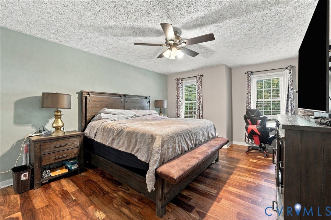 Bedroom featuring wood-finish flooring, a ceiling fan with integrated lighting, and double-hung windows