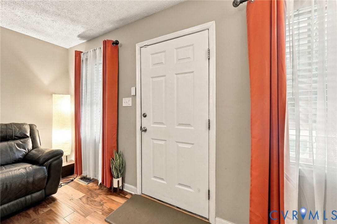 Entry area featuring wood-finish flooring, a six-panel door, and dual windows with window blinds