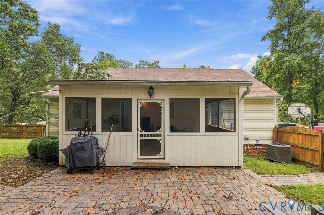 Screened-in porch featuring a paver patio, siding exterior, and exterior wall-mounted lighting