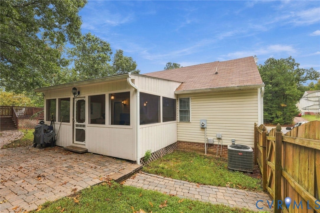 Screened porch featuring light-toned vertical siding, paver patio, brick foundation accents, and wood-finish perimeter fencing