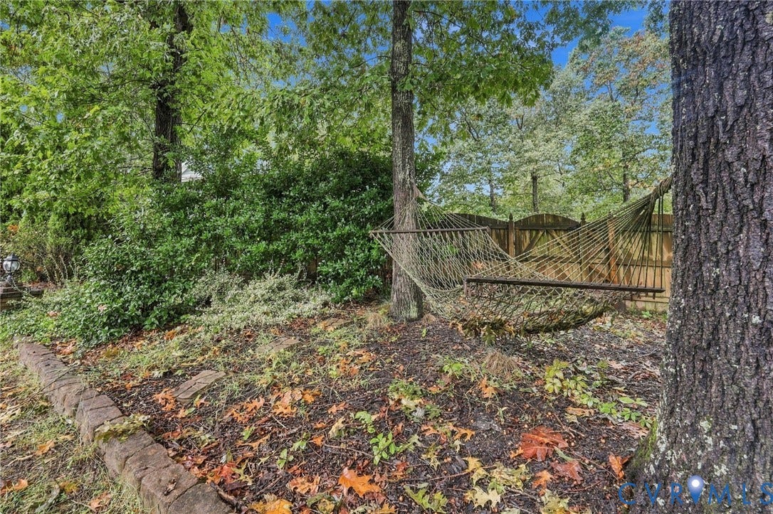Backyard featuring mature trees, a stone garden border, and wood privacy fencing