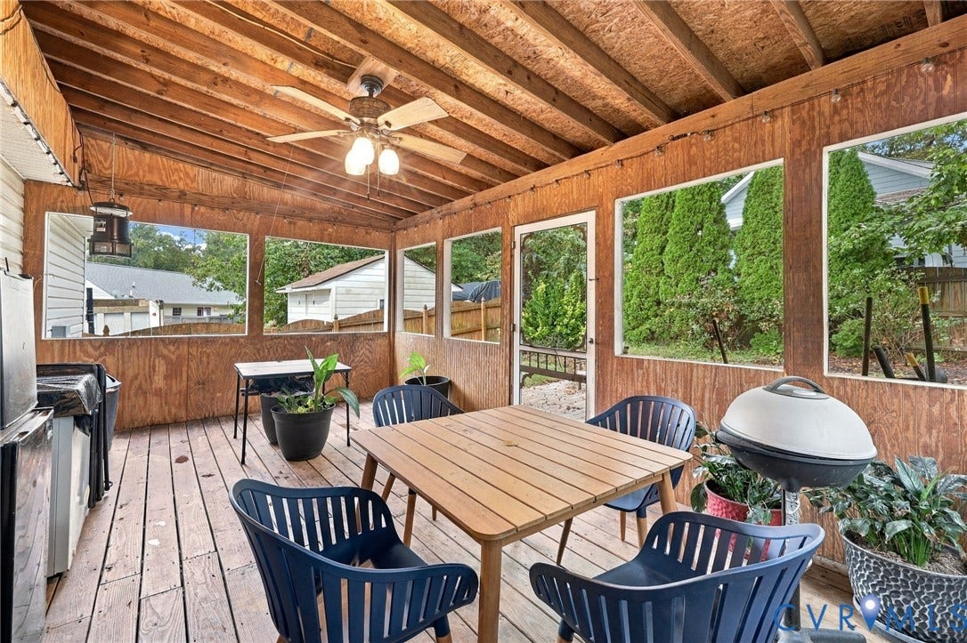 Screened-in porch featuring exposed wood ceiling beams, wood-plank flooring, large panoramic window panels, and an attached ceiling fan with integrated lighting
