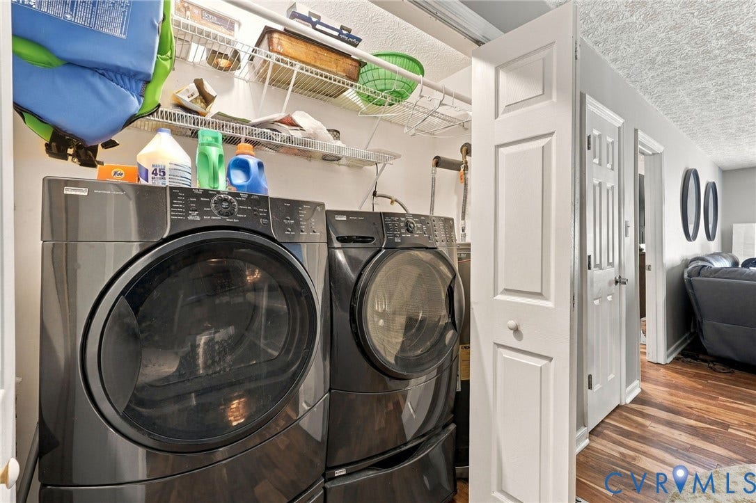 Laundry area featuring high-efficiency front-loading appliances, white bi-fold closet doors, and wire shelving