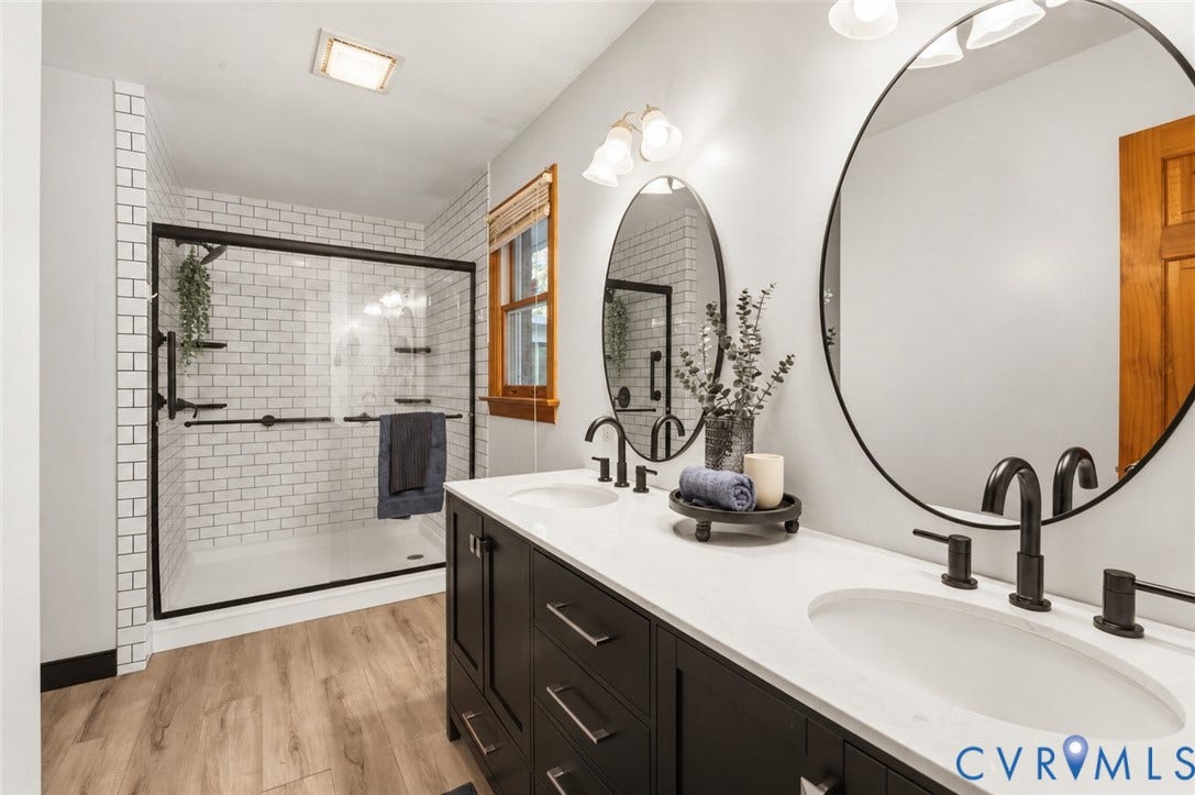 3621 Jefferson Highway, Mineral, VA 23093 Dual-sink vanity with matte black fixtures, white stone-composite countertop, subway tile shower enclosure with glass door, and wood-finish flooring