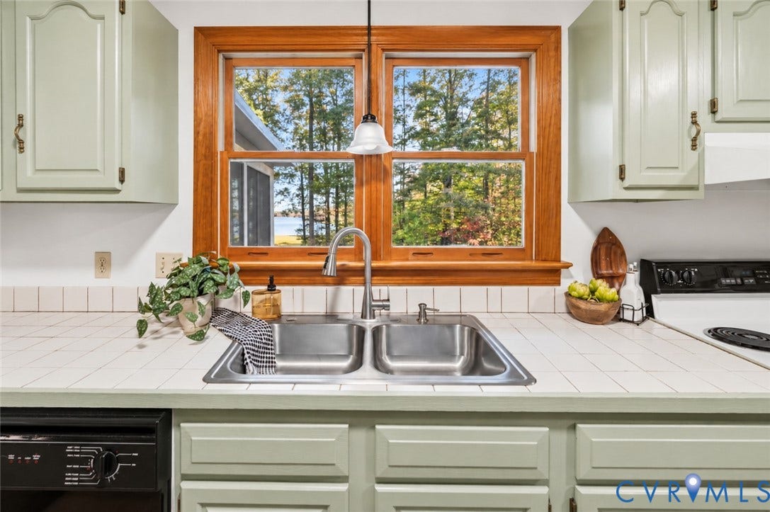 3621 Jefferson Highway, Mineral, VA 23093 Kitchen featuring painted cabinetry, tiled countertops, a double-basin stainless steel sink with a high-arch pull-down faucet, and a wood-framed window with exterior scenery
