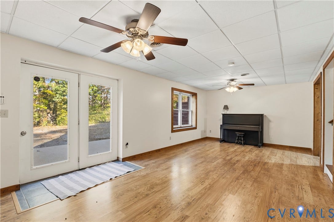 3621 Jefferson Highway, Mineral, VA 23093 Spacious room featuring wood-finish flooring, drop ceiling with dual ceiling fans, white glass-paneled double doors, and natural lighting provided by a window