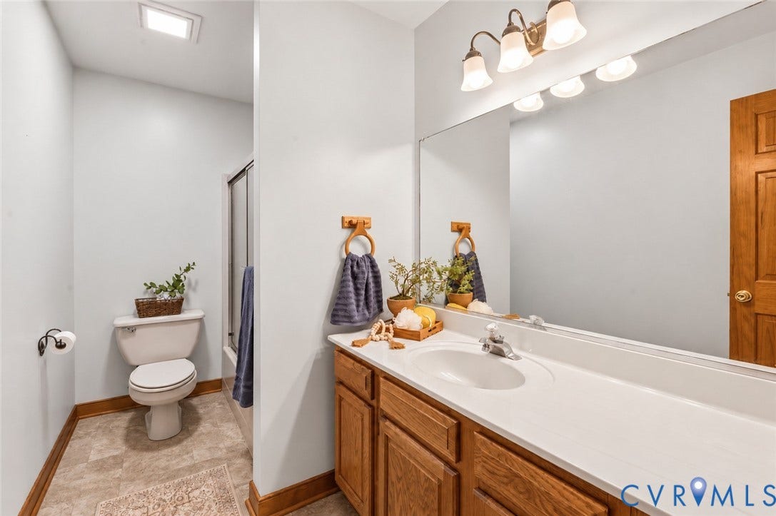 3621 Jefferson Highway, Mineral, VA 23093 Bathroom featuring a wood-finish vanity with a molded white countertop and integrated sink, full-width wall mirror, tri-light fixture, and shower enclosure