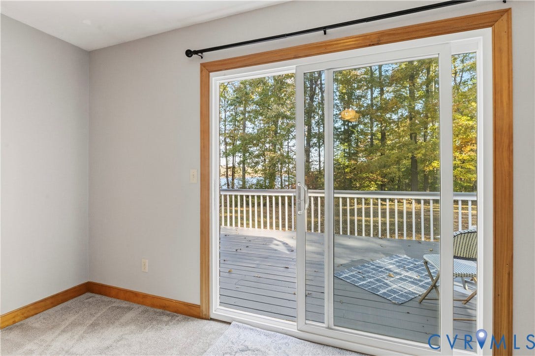 3621 Jefferson Highway, Mineral, VA 23093 Sliding glass door with natural wood casing, revealing an exterior deck with white railing and surrounding tree foliage