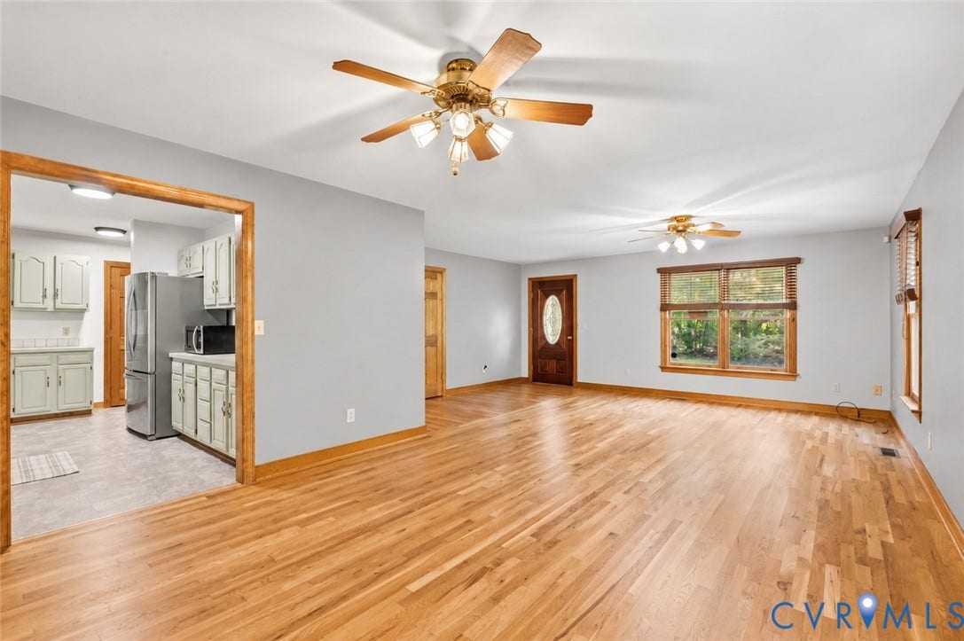 3621 Jefferson Highway, Mineral, VA 23093 Open living area featuring wood-finish flooring, natural wood trim, dual ceiling fans, and a solid wood entry door with an oval glass insert