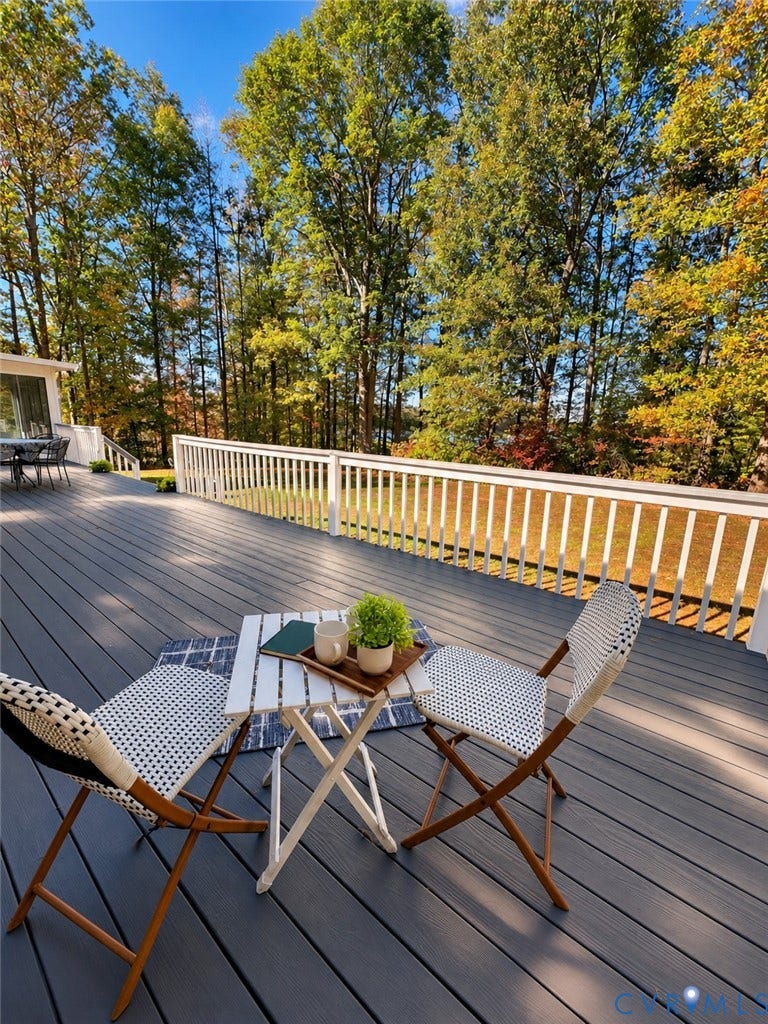 3621 Jefferson Highway, Mineral, VA 23093 Expansive wood-finish deck with white vertical-spindle railing, set against a backdrop of mature trees