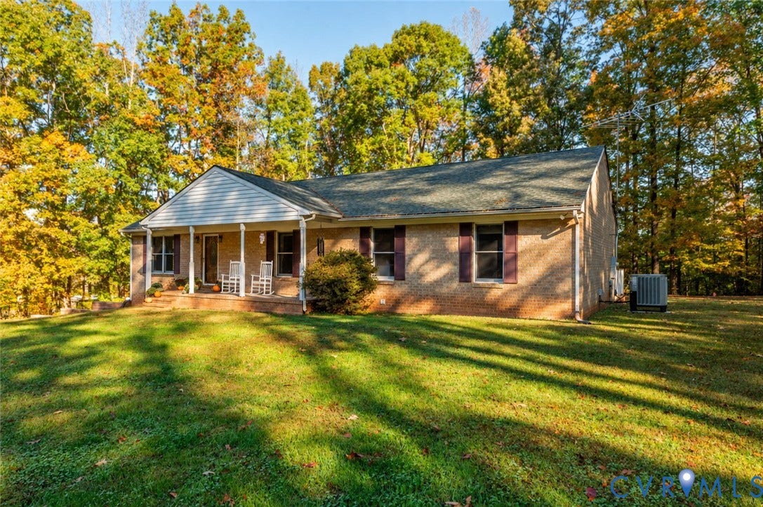 3621 Jefferson Highway, Mineral, VA 23093 Brick exterior featuring a covered front porch, dark-toned shutters, and mature wooded surroundings