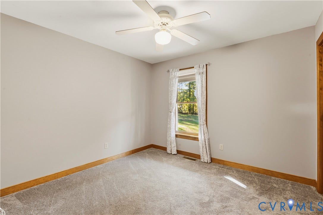 3621 Jefferson Highway, Mineral, VA 23093 Neutral-toned interior space featuring carpeting, a white ceiling fan with integrated lighting, and a single-pane window with wood trim