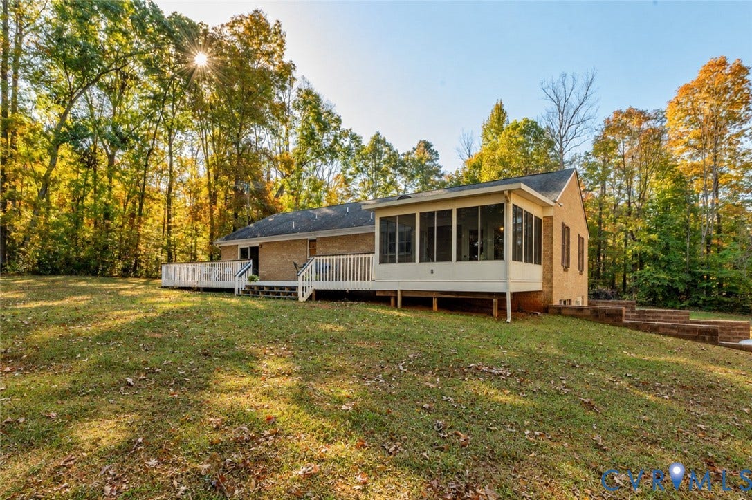 3621 Jefferson Highway, Mineral, VA 23093 Brick exterior featuring a screened porch, expansive raised deck with white railing, and tiered masonry retaining wall