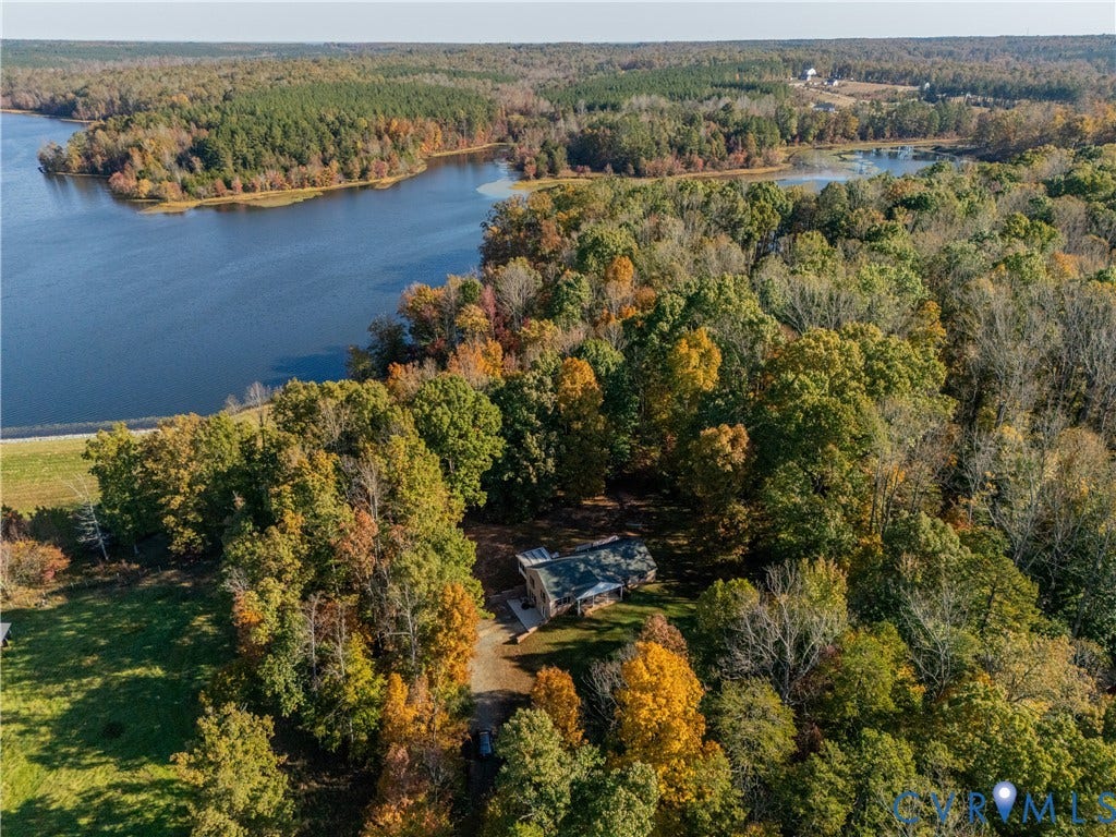 3621 Jefferson Highway, Mineral, VA 23093 Aerial perspective of a residence situated on a wooded lot, featuring extensive shoreline frontage, mature deciduous and evergreen trees, and a gravel driveway