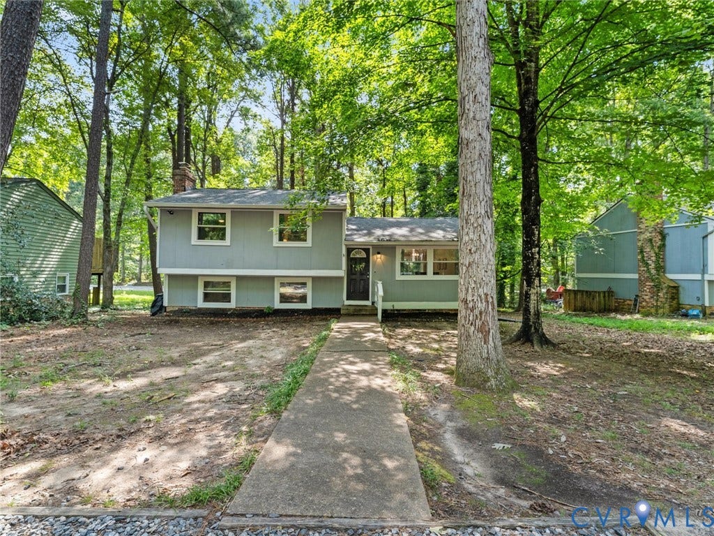2703 Sutters Mill Court, Sutters Mill, Chesterfield, VA 23112 Split-level exterior featuring light gray horizontal siding, a central front entry, concrete walkway, and mature wooded surroundings