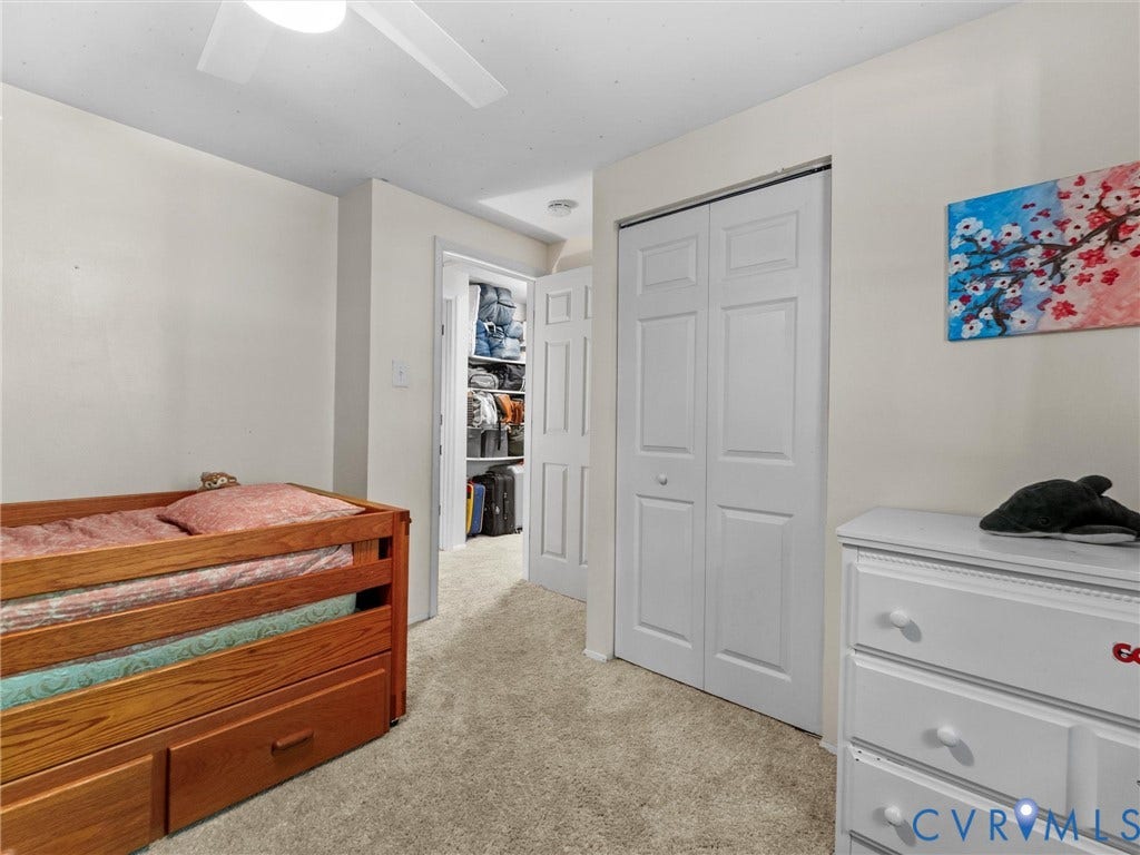 2703 Sutters Mill Court, Sutters Mill, Chesterfield, VA 23112 Neutral-toned room featuring wall-to-wall carpeting, a white paneled closet door, a ceiling fan, and a walk-in storage area with integrated shelving