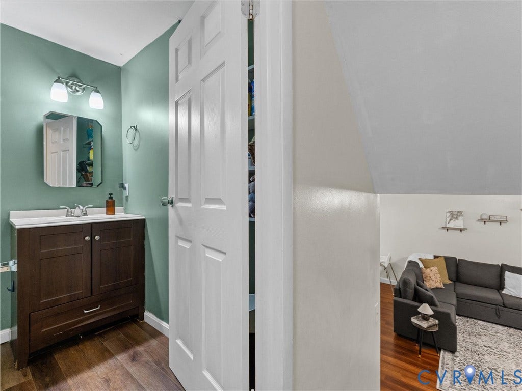 2703 Sutters Mill Court, Sutters Mill, Chesterfield, VA 23112 Dark wood vanity with a stone countertop, wall-mounted two-light fixture, bevel-edged mirror, and wood-finish flooring