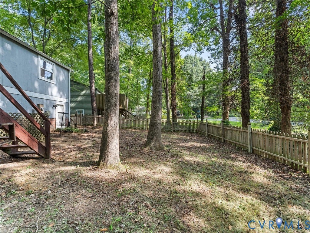 2703 Sutters Mill Court, Sutters Mill, Chesterfield, VA 23112 Wooded backyard featuring mature trees, a wooden picket perimeter fence, and an elevated wood staircase