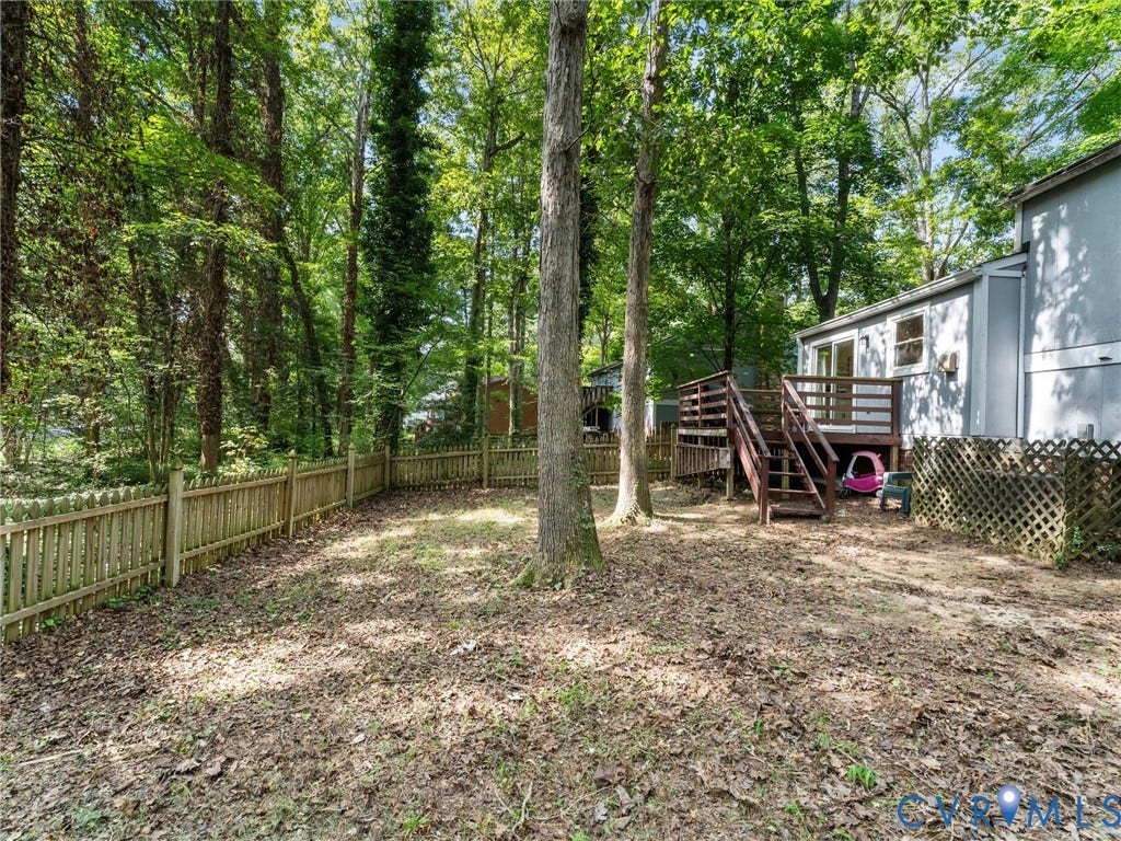 2703 Sutters Mill Court, Sutters Mill, Chesterfield, VA 23112 Backyard featuring a wood deck, wood picket fencing, lattice screening, and mature trees