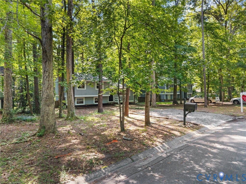 2703 Sutters Mill Court, Sutters Mill, Chesterfield, VA 23112 Two-story residence featuring light gray siding, a gravel driveway, and a natural, wooded lot