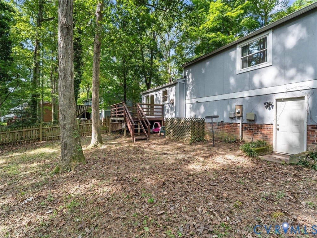 2703 Sutters Mill Court, Sutters Mill, Chesterfield, VA 23112 Exterior rear featuring a brick and wood-panel facade, elevated wood deck with stairs, and mature trees on a partially fenced lot