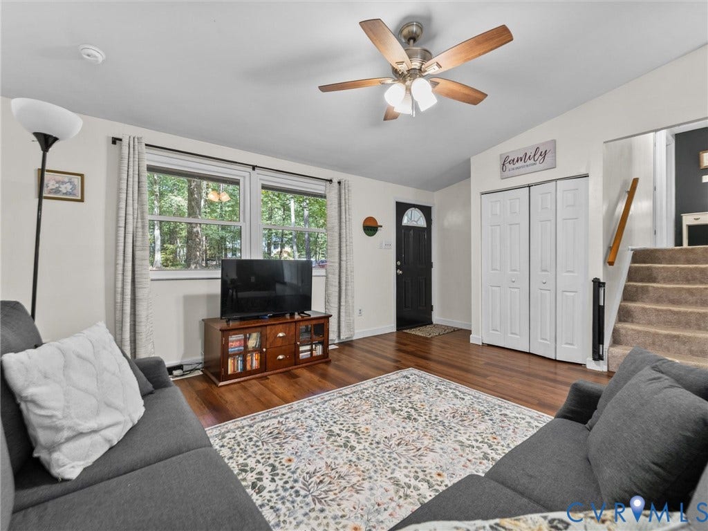 2703 Sutters Mill Court, Sutters Mill, Chesterfield, VA 23112 Living area featuring wood-finish flooring, a multi-blade ceiling fan with integrated light fixture, dual-panel closet doors, and windows with multi-pane glass