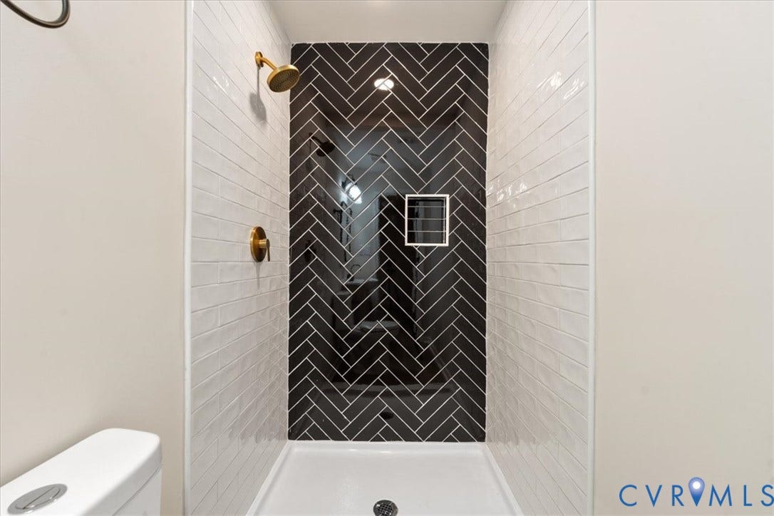 524 St Matthew Street, The Heights, Petersburg, VA 23803 Shower enclosure featuring a black herringbone tile accent wall, white subway tile surround, brass-finish shower hardware, and a built-in recessed wall niche