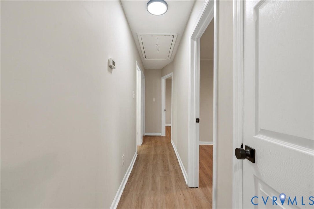 524 St Matthew Street, The Heights, Petersburg, VA 23803 Interior hallway featuring wood-finish flooring, crisp neutral walls, white interior doors with matte black hardware, and a flush-mount circular ceiling light