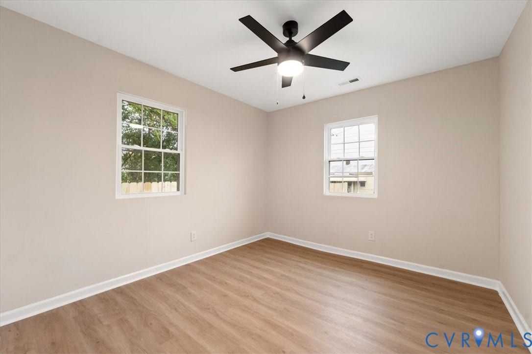 524 St Matthew Street, The Heights, Petersburg, VA 23803 Interior room featuring wood-finish flooring, neutral wall paint, two dual-pane windows, and a matte black ceiling fan with integrated lighting