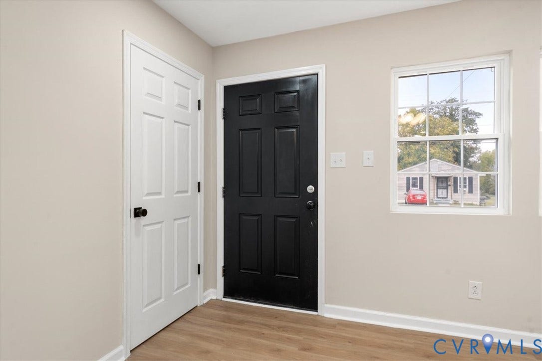 524 St Matthew Street, The Heights, Petersburg, VA 23803 Entryway featuring wood-finish flooring, a six-panel exterior door in matte black, a matching six-panel interior door, and a single-hung window with a grid pattern