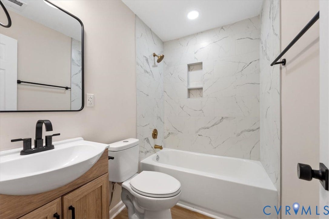 524 St Matthew Street, The Heights, Petersburg, VA 23803 Bathroom featuring a wood-finish vanity with a white vessel sink, matte black faucet, wall-mounted mirror, and a tub-shower combination with floor-to-ceiling surround and built-in recessed shelving