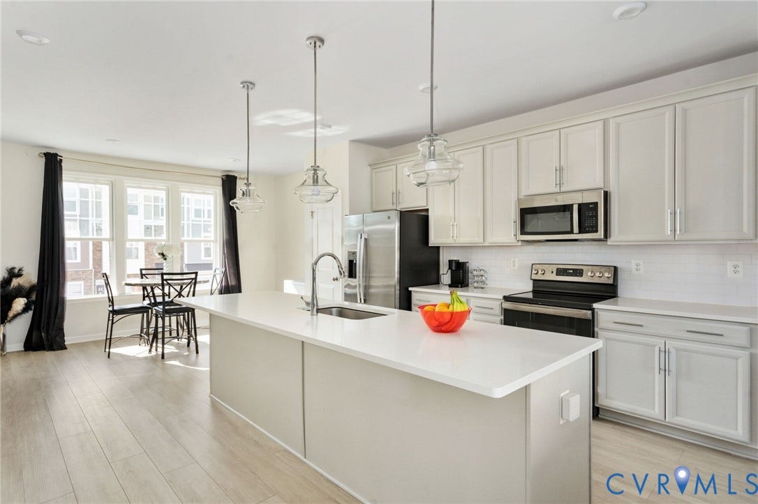 640 Rivanna Hill Road, Glen Allen, VA 23060 This bright, open kitchen features white cabinetry, stainless steel appliances, a subway tile backsplash, and a spacious island with pendant lighting, all flowing into a sunny dining area.