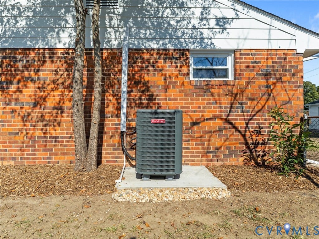 3303 Jowin Lane, Henrico, VA 23223 Exterior elevation featuring red brick masonry, white horizontal siding, a single-pane window, and a central HVAC unit mounted on a concrete slab