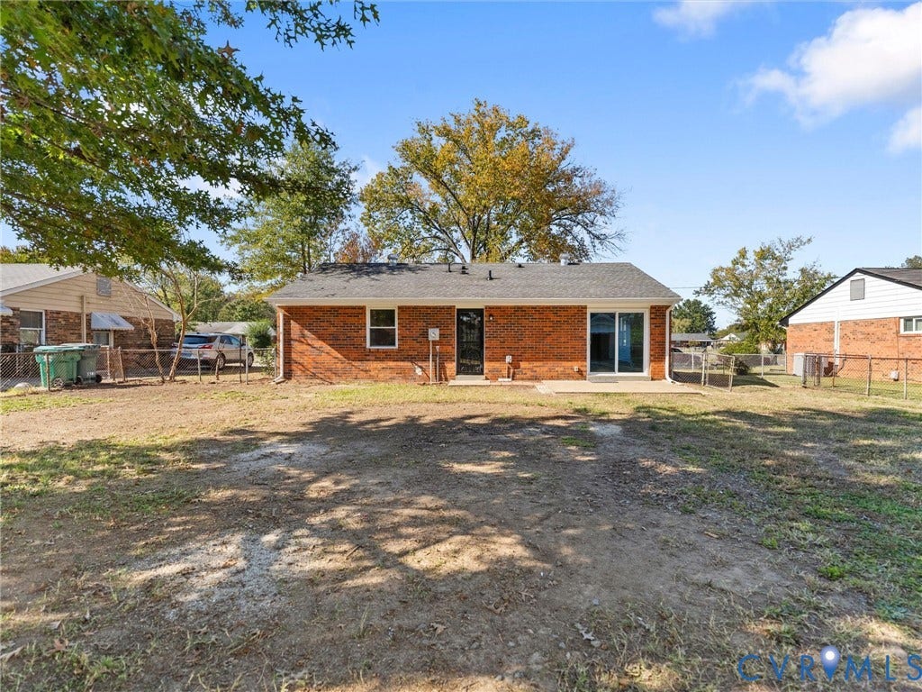 3303 Jowin Lane, Henrico, VA 23223 Full-brick exterior featuring a shingled roof, sliding glass doors, and a fenced-in rear yard with mature trees